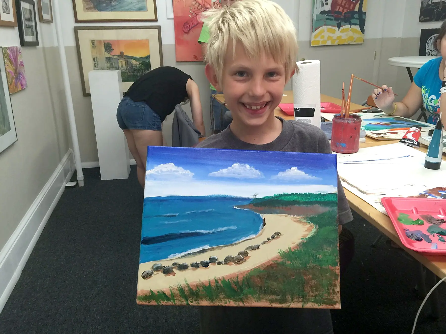 A young artist proud of a finished beach painting