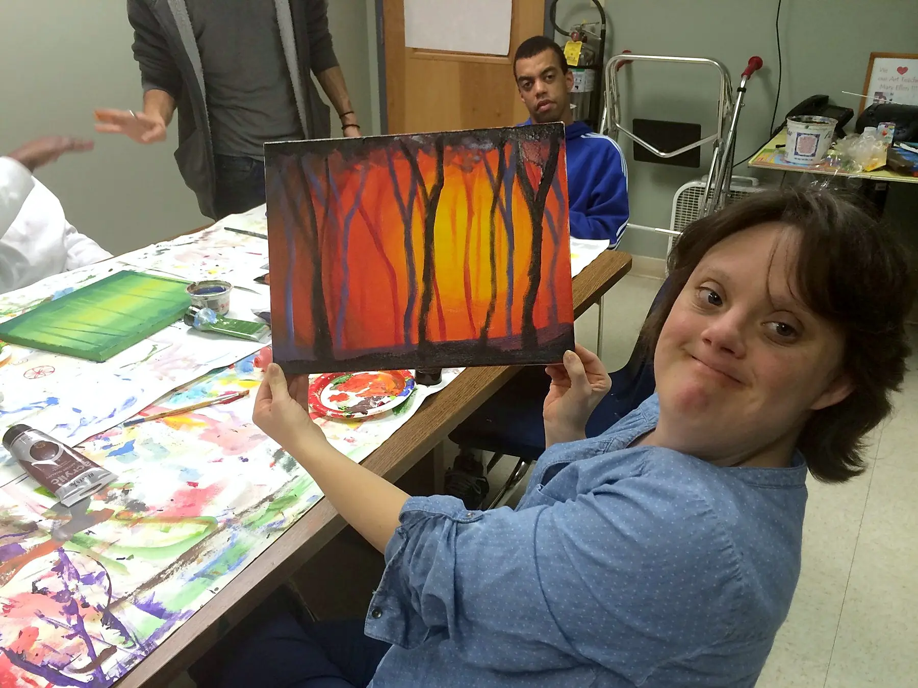 A student holding up a sunset painting