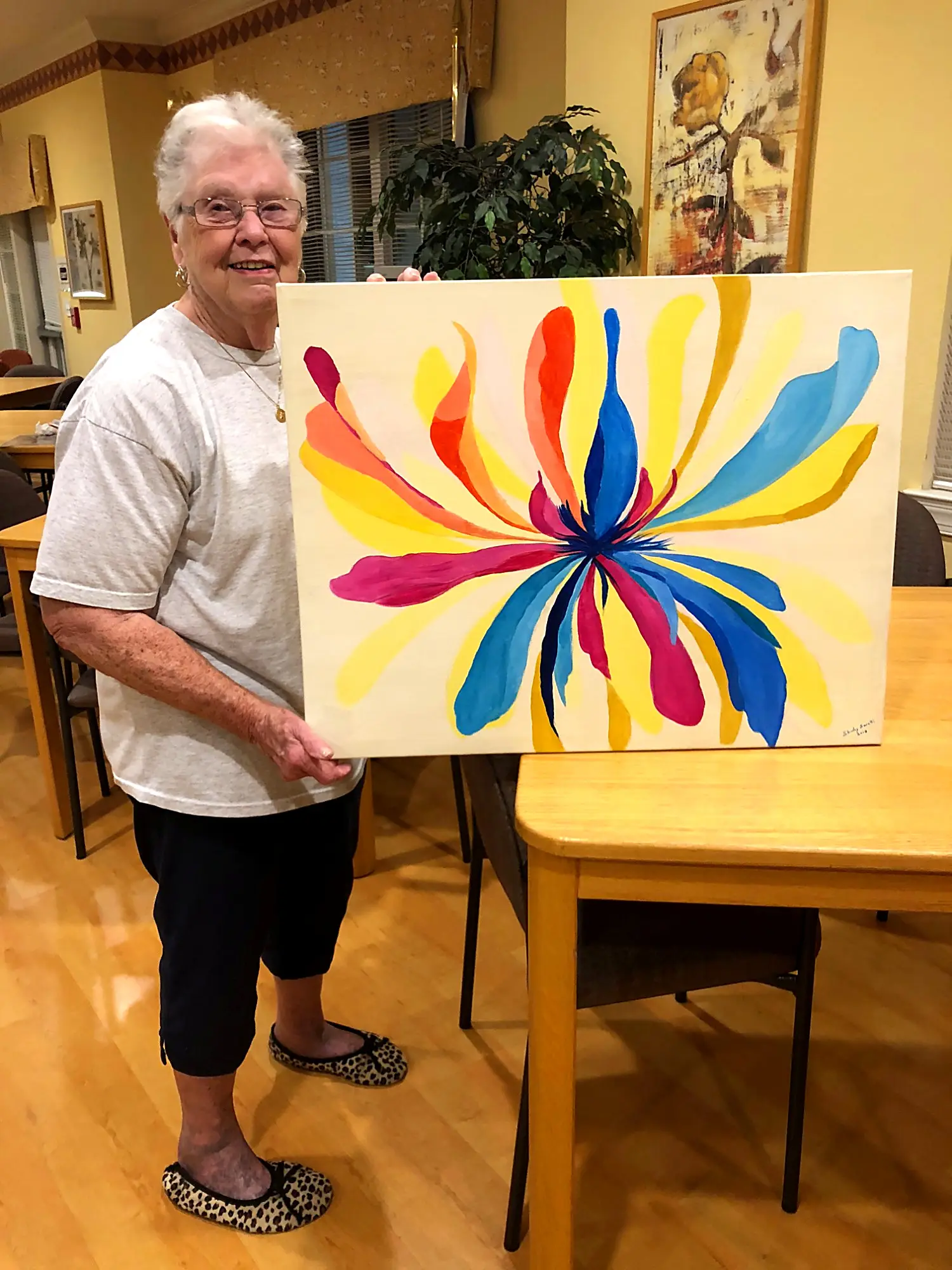 A senior student holding a finished abstract flower painting