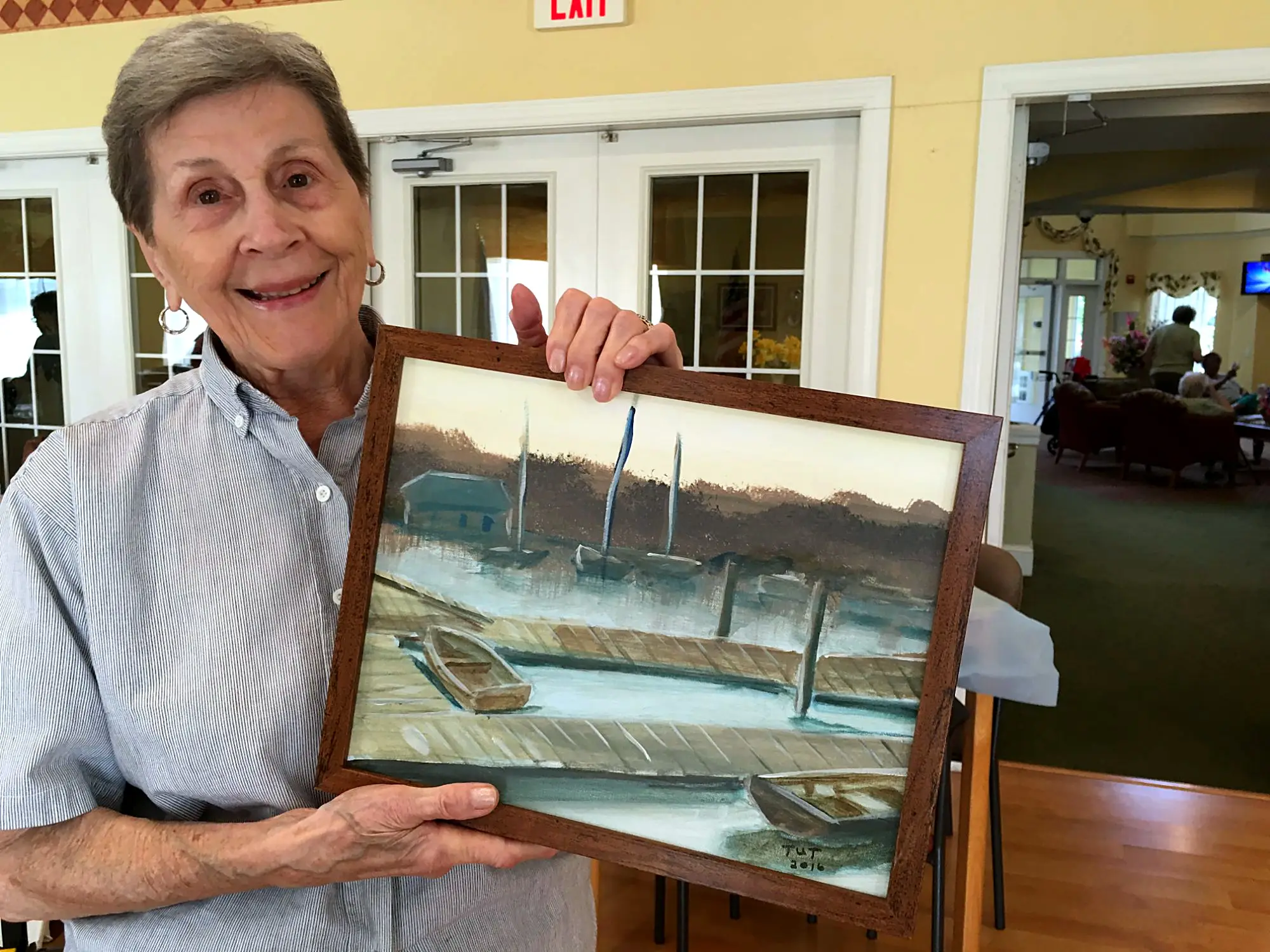 A senior artist with a framed harbor painting