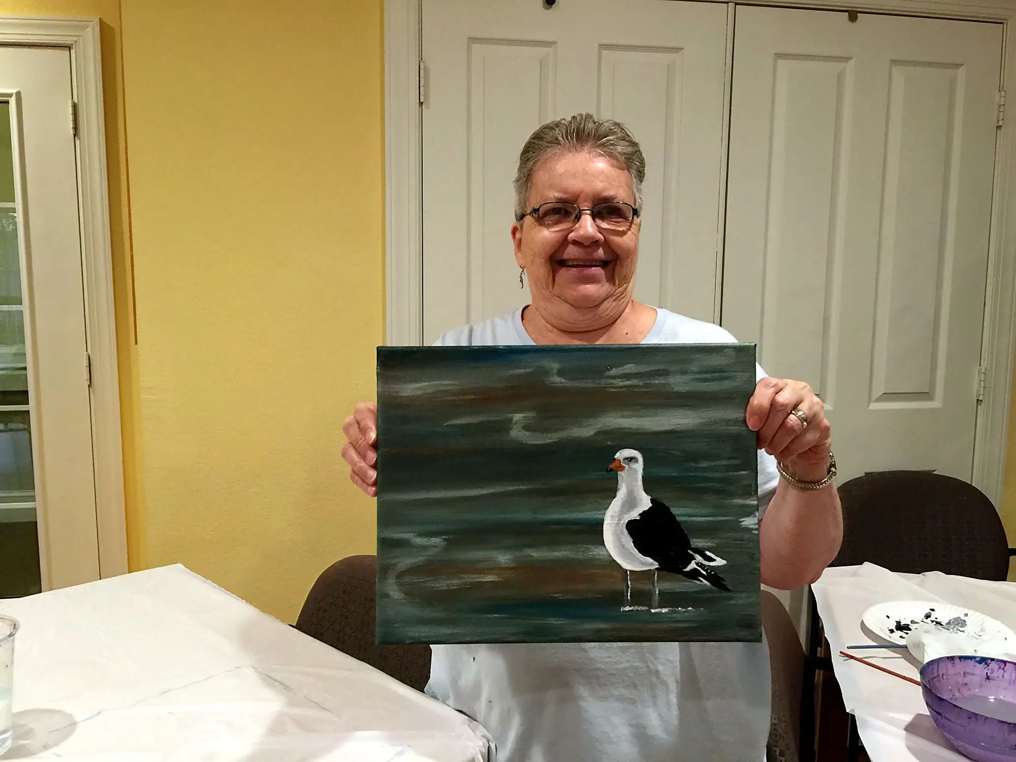 A senior artist holding a seagull painting
