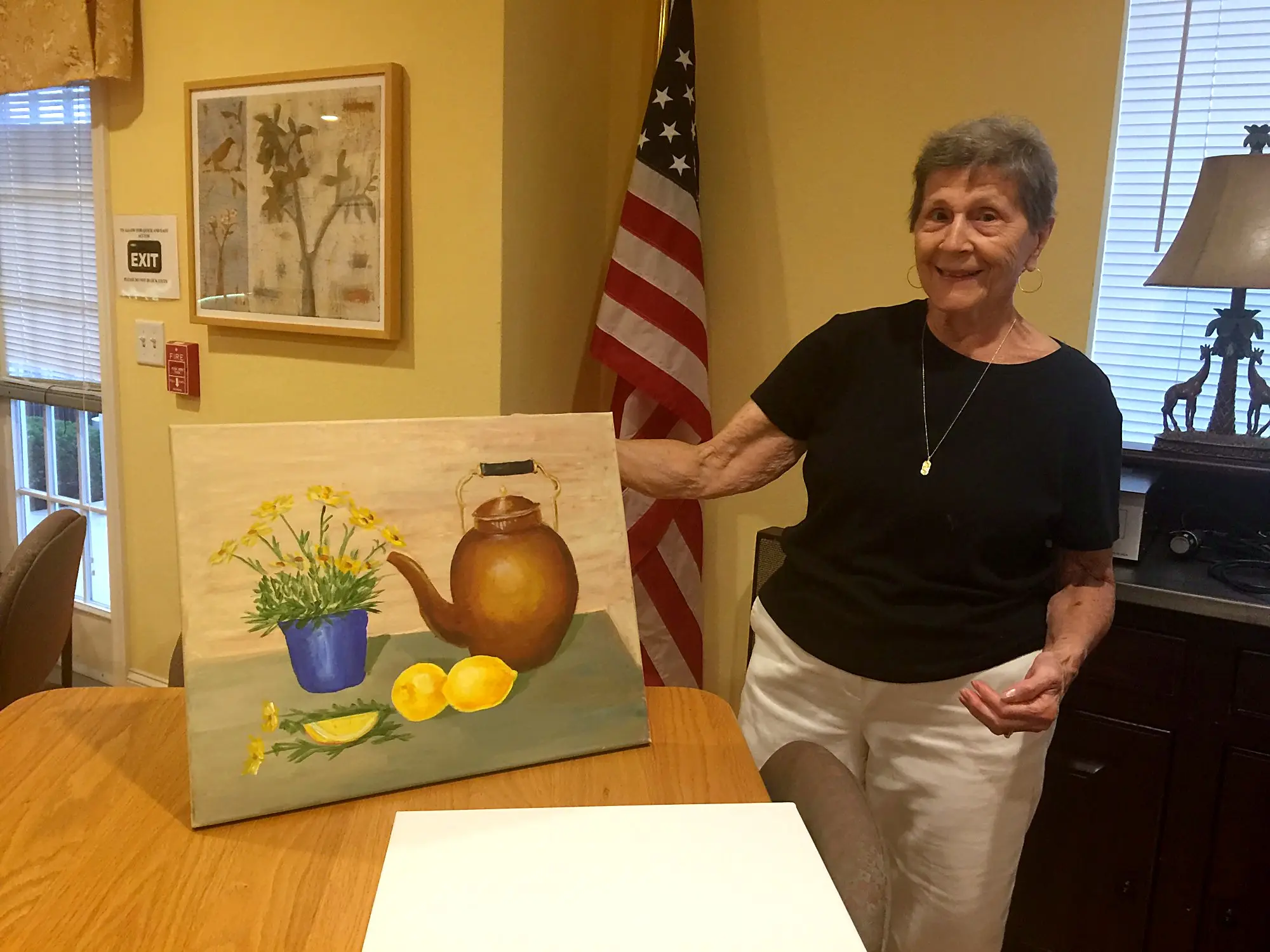 A senior artist beside a still life of a teapot, flowers and lemons